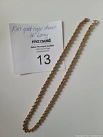 Chain laid out on white surface with MaxSold card showing handwritten specs