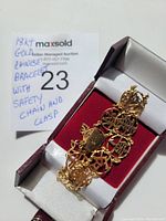 Bracelet displayed in red and white jewelry box, showing openwork circular character links and clasp