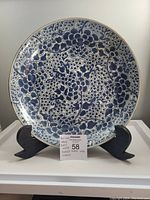 Front view of hand-painted blue floral porcelain plate on stand