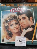 Framed album cover of GREASE with John Travolta and Olivia Newton-John, showing autograph and label note.