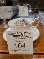 Side view of teacup with floral design and gold-trimmed handle next to matching saucer.