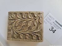 Top view of carved stone jewelry box showing intricate floral and berry carving with dark inlay on lid