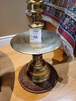 Photo of brass and teak wood floral motif stand alone, showing its round shape and carved details