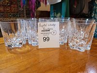 8 clear crystal whiskey tumblers arranged on wooden surface with auction lot card visible.
