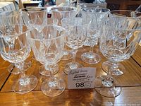 Front view of 10 crystal wine glasses including 6 red wine and 4 white wine glasses on a wooden surface with price tag.
