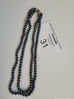 Full view of double strand pearl necklace laid flat with auction tag