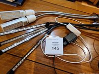 Overview of two sets of grow lights with multiple LED strips, power cords and clamps on wooden surface.