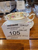 Photo of the teacup stacked on the saucer with auction label showing Hammersley Bone China.