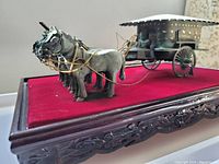 Side-angle view showing the four horses and detailed cart on red fabric base inside the plexiglass case with rosewood frame.