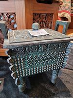 Ice bucket with intricate carved geometric and textured patterns, square body, short legs, and visible handles.