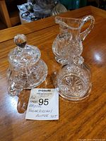 Full set of sugar bowl with lid, creamer, and butter dish displayed on wooden table.