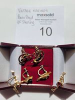 Three pairs of vintage screw-back earrings in an open burgundy box with red velvet interior, showing detailed designs and screw-back mechanisms.