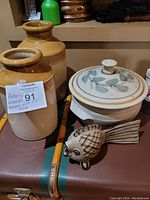 Overall view of the pottery items showing crocks, tureen, and fish sculpture