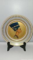 Front view of the decorative plate showing Queen Nefertiti profile with gold and blue ornamental border.