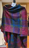 Multi-color plaid shawl hanging, showing vibrant colors of red, blue, green, and purple, soft fabric.