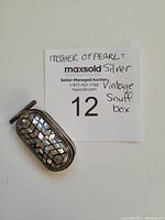 Closed view of the vintage silver snuff box showing the mother of pearl inlay with geometric design on the lid.