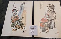 Two art prints on flat surface showing floral and rock imagery, calligraphy, and artist seals.