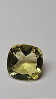 Close-up photo of the 5.45 carat cushion cut lemon citrine gemstone showing its color, cut, and clarity on a white background.
