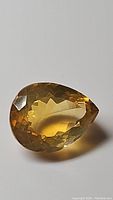 Close-up photo of the pear-shaped golden citrine gemstone showing facets and color.