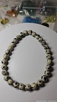 Photo of dalmatian jasper stretchy bracelet showing round cream beads with black spots, arranged on a white circular display surface.