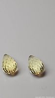 Pair of lemon citrine briolette cut gemstones displayed against a plain background showing facets and clarity.