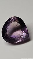 Close-up clear photo of the single pear-shaped faceted Brazilian amethyst gemstone, showing deep purple color and reflections.