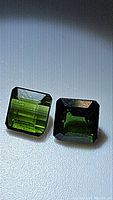 Pair of natural green octagon cut tourmaline gemstones on a light background, showing color and facets clearly