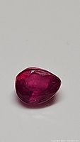 Close-up image of a pear-shaped blood red ruby showing its facets and natural inclusions.