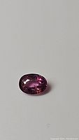 Oval cut padparadscha sapphire stone showing pinkish orange color and clarity.