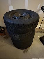 Four stacked tires mounted on steel rims seen from top and side angle.