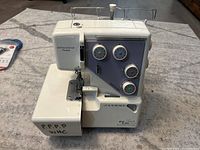 Front-left angle showing main body, tension dials, and differential feed area.