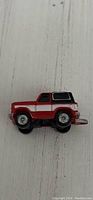 Top down side view of the red and white Micro Machines Galoob pick up truck with black cap and silver hitch on light wood surface.