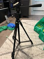 Full view of the Vanguard MG-2 OS tripod standing on carpet with telescoping legs extended, pan/tilt handle visible, and the leveling bubble clearly shown.