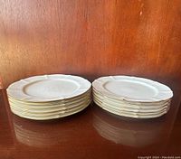 Two stacks of Noritake Chandon oval plates showing embossed floral details and scalloped edges with gold trim