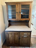 Front view of two-piece oak Hoosier-style bakers cabinet with upper glass doors and lower porcelain countertop