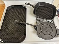 Overview of all three cast iron items on stovetop: rectangular ridged griddle, square ridged grill pan, and tortilla press skillet