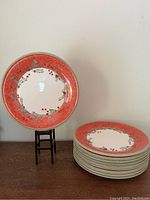 Set of 12 vintage Christmas plates stacked with one plate displayed on a black stand showing the decorative design.