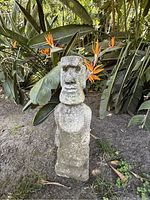 Front view of the Easter Island Moai style stone garden statue, showing rough textured surface and typical Moai facial features.