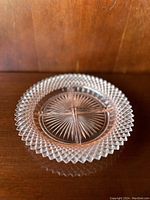 Single pink glass plate with starburst pattern on a wooden surface