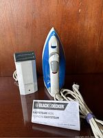 Front view of Blue and white Black & Decker EasySteam iron and white Remington steamer with black steam head plus product card