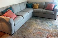 Full view of gray sectional couch with decorative pillows from left angle