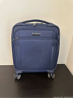 Front view of blue Samsonite carryon suitcase showing front zippered compartments and Samsonite metal badge.