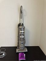 Front view of Shark Navigator Deluxe vacuum cleaner showing full unit with hose and wand attached, manual placed at base.