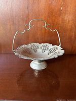 Photo of a vintage silver basket showing the scalloped and pierced bowl with a curved decorative handle and pedestal base.