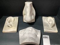 Top view of set showing two ears, nose, and lips/chin sculpture on flat surface.
