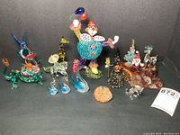 Full view of the entire collection showing all 15 vintage hand blown glass figurines including the clown, swans, dragon, giraffe, hummingbird, witch, pumpkin, cat, and Christmas figures on wood base.