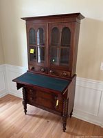 Full frontal view of secretary desk showing upper glazed cabinet and drop-front desk surface.
