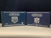 Two blue binders side by side: left titled “Super Bowl XXV” crest, right titled “NFL Super Bowl Patch Collection” shield.