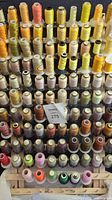 Wooden storage rack filled with multiple rows of machine embroidery thread spools in various yellow and brown shades, some wrapped.