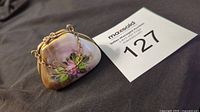 Mini handbag-shaped Limoges porcelain box with floral design and metal clasp, showing front with chain handle and painted roses.